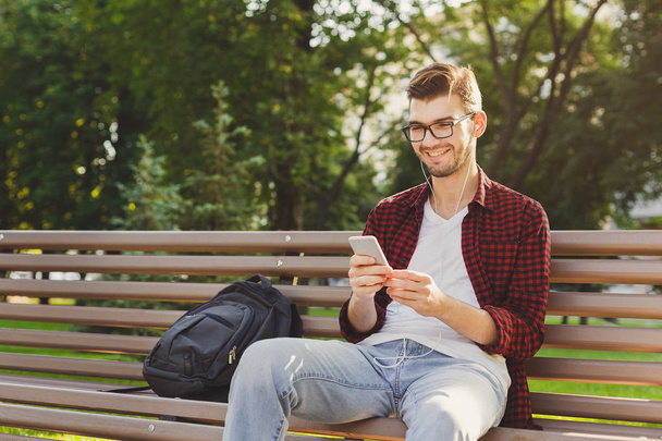 Happy young man using smartphone outdoors - 写真・画像