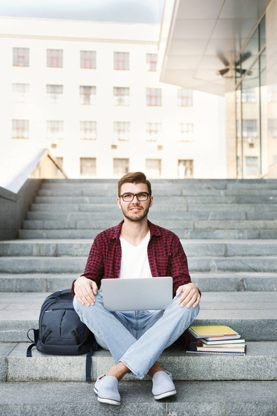 Студент сидить на сходах з ноутбуком на відкритому повітрі
 - Фото, зображення