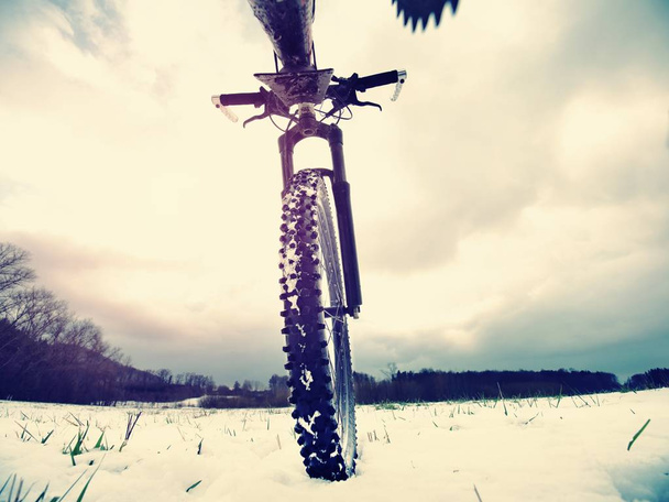 Nieve de invierno montada en bicicleta de montaña. Clima extremo, camino resbaladizo en el campo, vista cercana
 - Foto, imagen
