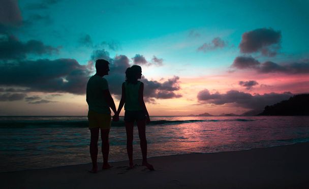 sunset silhouette of young couple in love hugging at beach - Photo, Image