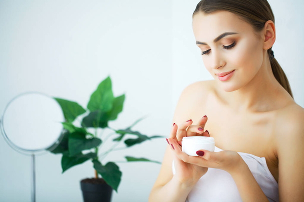 Una mujer hermosa usando un producto para el cuidado de la piel, crema hidratante o loti
 - Foto, imagen