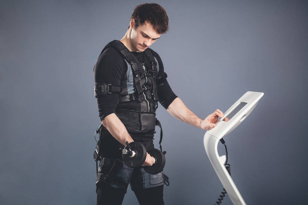 man in Electrical Muscular Stimulation suit standing with dumbbells - Photo, image