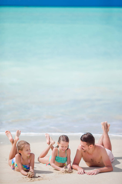 Padre e hijos pequeños disfrutando de vacaciones tropicales de verano en la playa. Familia jugando en la playa
 - Foto, imagen
