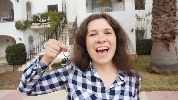 glückliche junge Frau, die ein neues Zuhause bezieht. Schlüssel der neuen Immobilie zeigen - Filmmaterial, Video