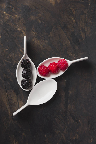 Spoons with raspberry and blackberries background black - Fotó, kép