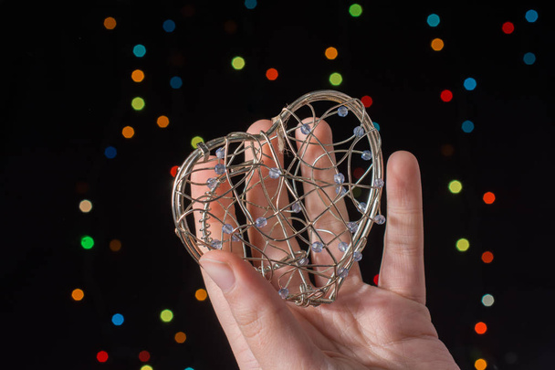 Coração em forma de gaiola de metal na mão no fundo de luz bokeh - Foto, Imagem
