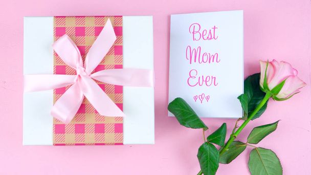 Ημέρα της μητέρας επιβάρυνση με τριαντάφυλλο, καλύτερη μαμά ποτέ κάρτα και δώρο σε ροζ πίνακα. - Φωτογραφία, εικόνα