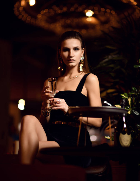 Beautiful sexy fashion brunette woman in expensive interior restaurant drinking champagne waiting on dark cafe  - Фото, зображення