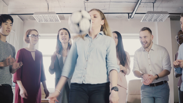 Boldog az irodai alkalmazottak tartsa a fizikai aktivitás. Fiatal többnemzetiségű kollégák ünneplése, játszani a futball-labda 4k - Felvétel, videó