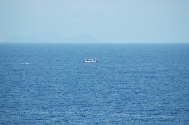 Ένα μικρό αλιευτικό σκάφος που ακολουθείται από γλάροι. - Φωτογραφία, εικόνα