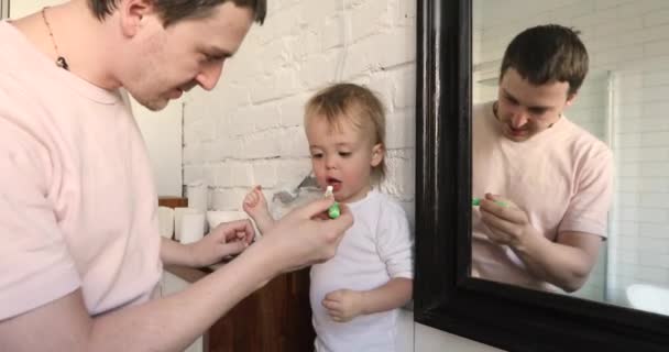 Tata jest szczotkowanie zębów próchnica do jego syn łazienka - Materiał filmowy, wideo