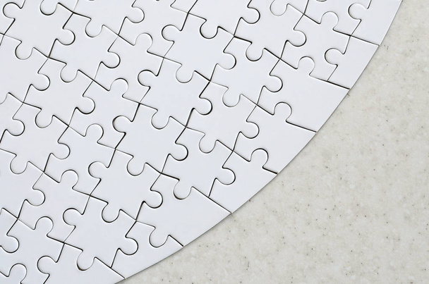 Un puzzle blanc dans sa forme complète repose sur une surface de pierre traitée. Image texturée avec espace de copie
 - Photo, image