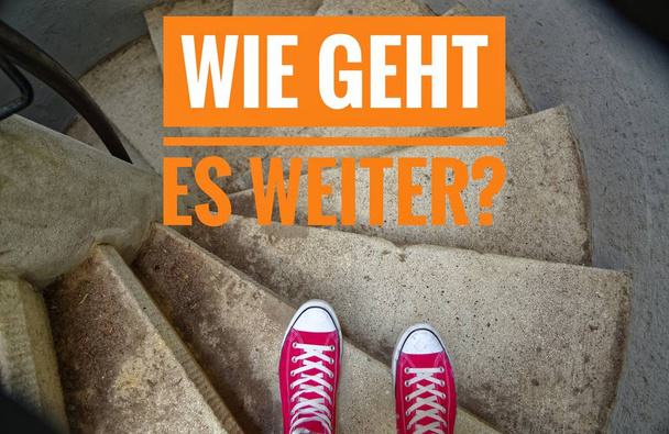 Czerwone trampki na spiralne schody gdy zjazd i napis w niemiecki Wie geht es weiter? w angielskim co dalej? - Zdjęcie, obraz