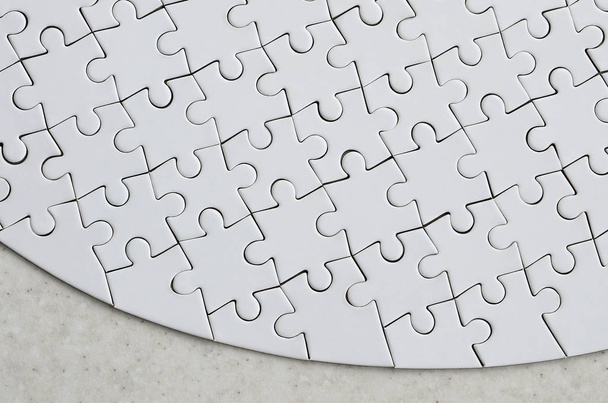 Een witte puzzel in het volledige formulier op een behandelde stenen oppervlak ligt. Getextureerde afbeelding met kopie ruimte - Foto, afbeelding