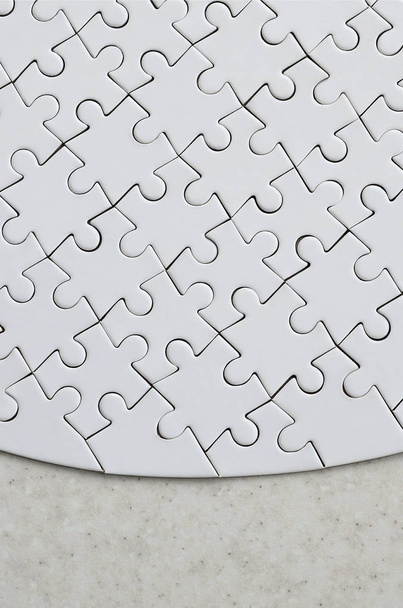 Un puzzle bianco nella forma completa si trova su una superficie di pietra trattata. Immagine strutturata con spazio di copia
 - Foto, immagini