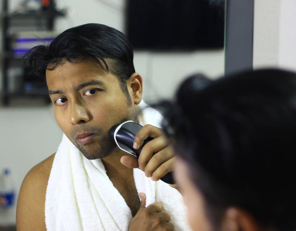 man lookingIndian asian after his appearance in front of a mirror beauty styling lifestyle. Shaving routine - Fotografie, Obrázek