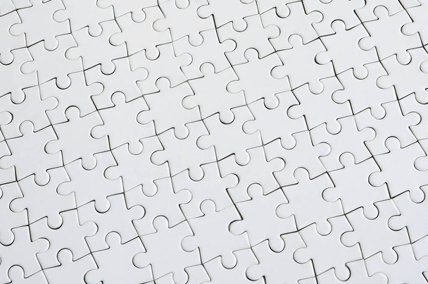 Close-up textuur van een witte puzzel in gemonteerde toestand. Bovenaanzicht. Veel onderdelen van een grote hele mozaïek zijn Verenigd - Foto, afbeelding