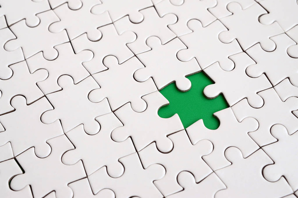 Het patroon van de close-up van een witte puzzel in geassembleerde staat met ontbrekende elementen vormen van een groene pad voor tekst. Kopiëren van ruimte - Foto, afbeelding