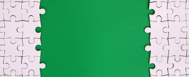 Θραύσμα από ένα διπλωμένο λευκό παζλ για το ιστορικό της μια πράσινη πλαστική επιφάνεια. Υφή φωτογραφία με αντίγραφο χώρο για το κείμενο - Φωτογραφία, εικόνα