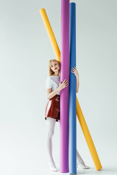 Fashionable blonde girl carrying colorful paper rolls - Фото, изображение