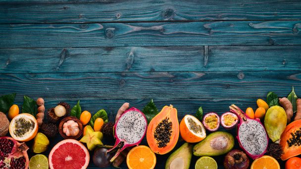 Tropical fruits, papaya, Dragon Fruit, rambutan, tamarind, cactus fruit, avocado, granadilla, carambola, kumquat, mango, mangosteen, passionfruit, coconut. On a wooden background. - Foto, afbeelding