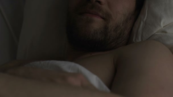 Gezonde tevreden man liggend in bed, denkend over zijn vriendin en glimlachen - Video