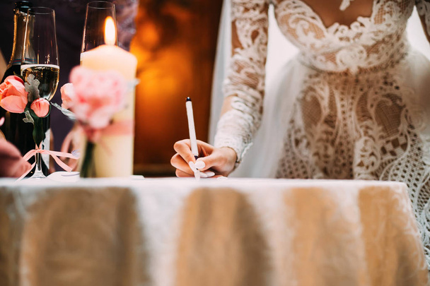η νύφη σε ένα όμορφο φόρεμα βάζει την υπογραφή σε ένα σημαντικό - Φωτογραφία, εικόνα