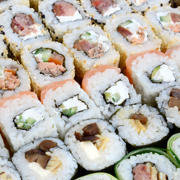 Close-up of a lot of sushi rolls with different fillings. Macro shot of cooked classic Japanese food. Background image - Photo, Image