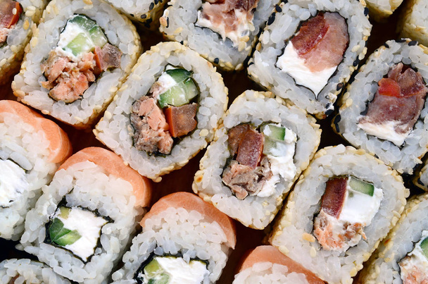 Κοντινό πλάνο μιας παρτίδας των σούσι κυλίνδρους με διαφορετικές γεμίσεις. Μακροεντολή πυροβολισμό κλασικό ιαπωνικό φαγητό. Εικόνα φόντου - Φωτογραφία, εικόνα