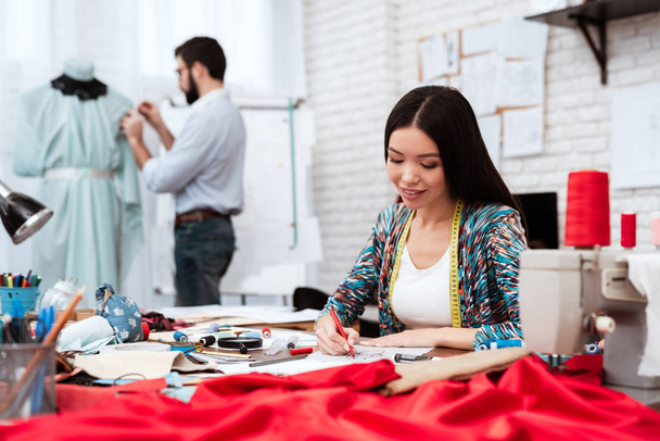 γυναίκες σχεδιαστής Σκίτσο κάνοντας ενώ ο άνθρωπος που εργάζονται σε μανεκέν στο ραφείο  - Φωτογραφία, εικόνα