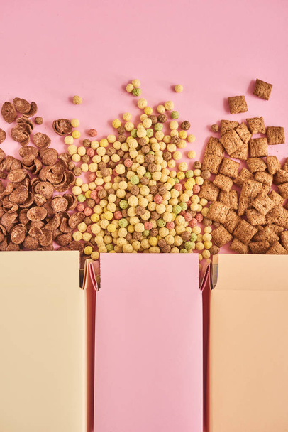Top view of colorful boxes with different types on cornflakes on pink background - Photo, Image