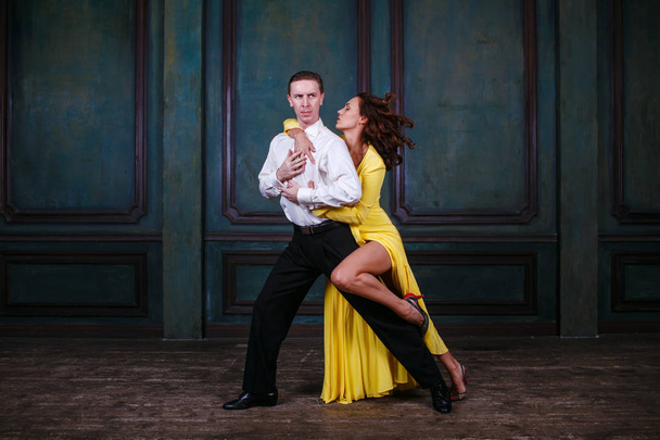 Mooie jongedame in gele jurk en man dance tango - Foto, afbeelding