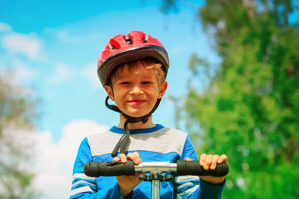 happy little boy with helmet riding scooter - Foto, Imagen