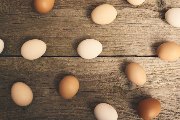 Widok zbliżenie z kurczaka świeże surowe jaja jasny brązowy drewniany stół tło. - Zdjęcie, obraz