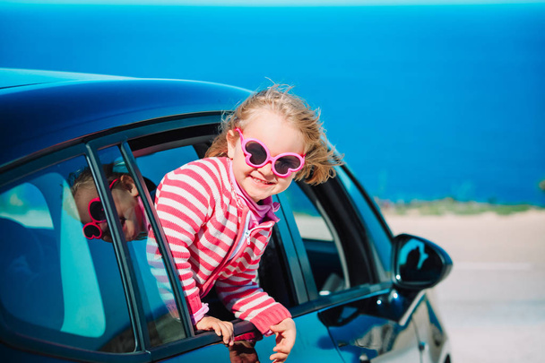glückliches kleines Mädchen genießt die Fahrt mit dem Auto auf See - Foto, Bild