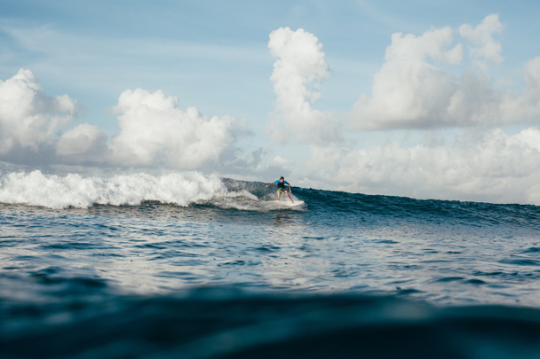 Junger Sportler im Neoprenanzug amüsiert sich an sonnigen Tagen auf dem Surfbrett - Foto, Bild