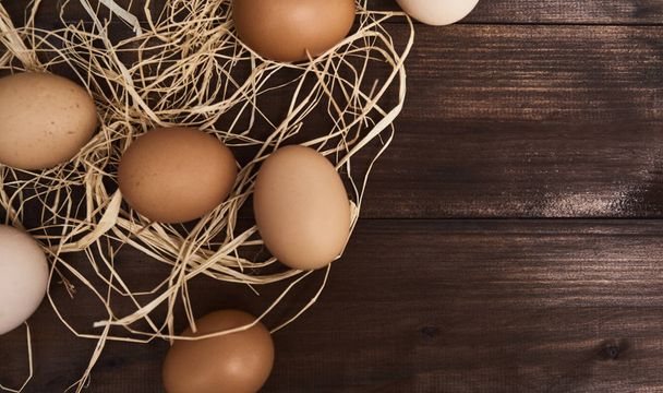 Uova di pollo fresche marroni con fieno che depone su fondo di legno
. - Foto, immagini