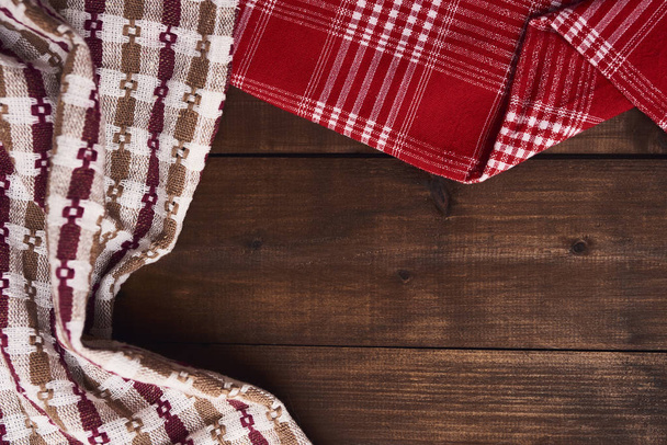 Фон коричневого сільського дерев'яного столу з різними барвистими кухонними рушниками
. - Фото, зображення