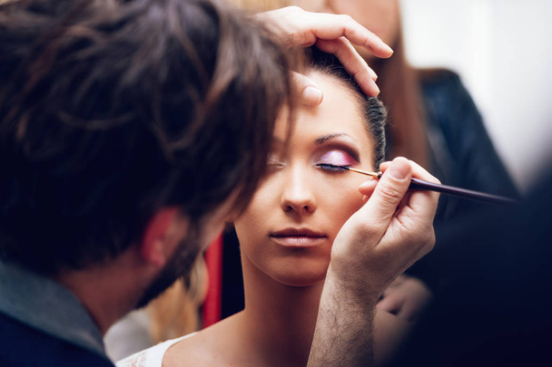 Κλείστε την προβολή του μακιγιάζ καλλιτέχνης ο άνθρωπος να πάρει eyeliner στο μοντέλο - Φωτογραφία, εικόνα