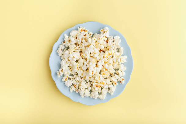 popcorn in a blue plate on a yellow background top view - 写真・画像