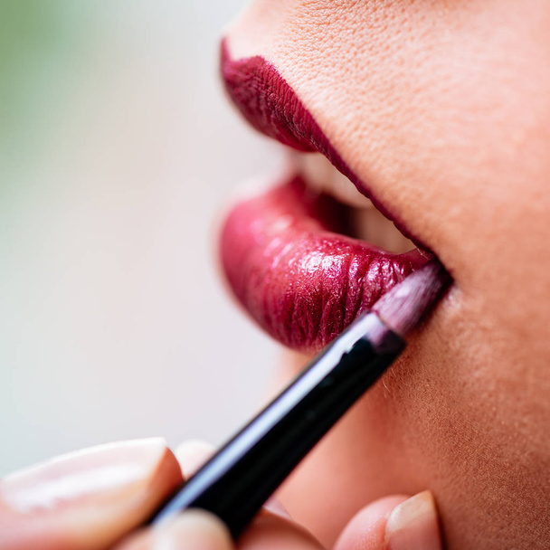 Close view of makeup artist applying perfect red lipstick to model - Φωτογραφία, εικόνα