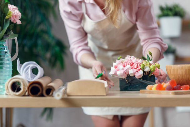 Imagem da florista mulher fazendo buquê de marshmallows, flores
 - Foto, Imagem
