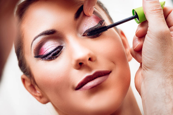 Maquillaje artista aplicando el rímel a modelo
 - Foto, imagen