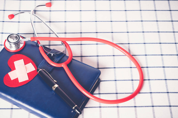 Dünya Sağlık günü sağlık ve tıbbi kavramı kırmızı stetoskop ve kırmızı kalp şekil üstünde mavi günlük defter - Fotoğraf, Görsel