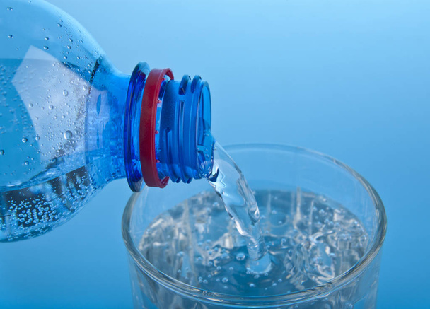 Butelka z wodą i szkło na niebieskim tle - Zdjęcie, obraz