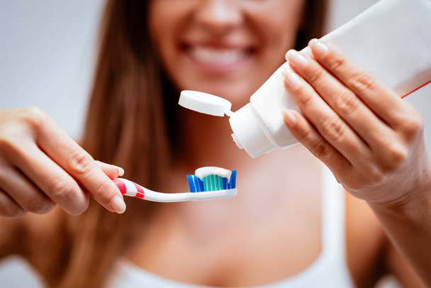 Близкий взгляд молодой женщины, чистящей зубы
 - Фото, изображение