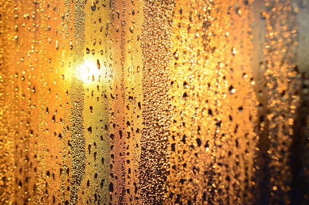 A textura do vidro enevoado com um monte de gotas e gotas de condensação contra a luz solar ao amanhecer. Imagem de fundo
 - Foto, Imagem