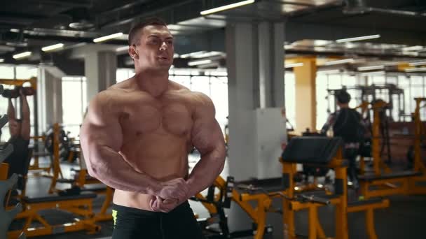 Hombre culturista posando y muestra los músculos cerca del espejo en el gimnasio
 - Imágenes, Vídeo