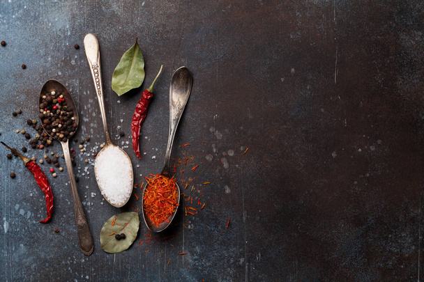 Spices in spoons over stone table. Cooking concept. Top view with space for text - Photo, Image