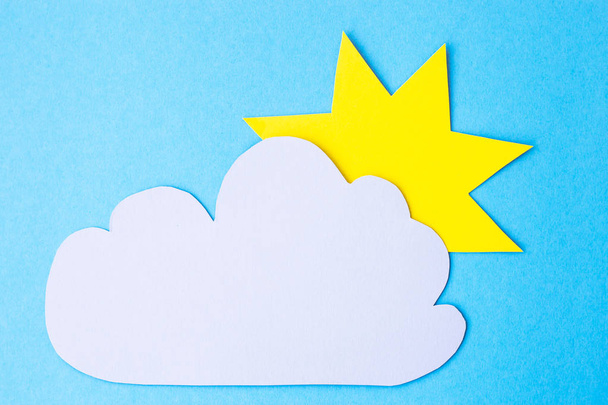 Sárga papír nap mellett egy szürke felhő a kék háttér. Felhős Időjárás fogalma - Fotó, kép